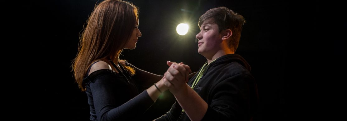 2 students performing with lighting in the background