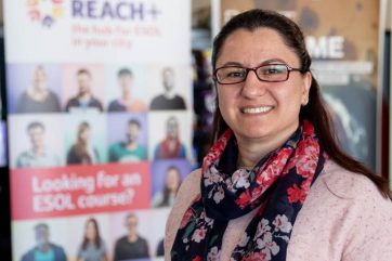 Woman standing in front of Reach+ banner